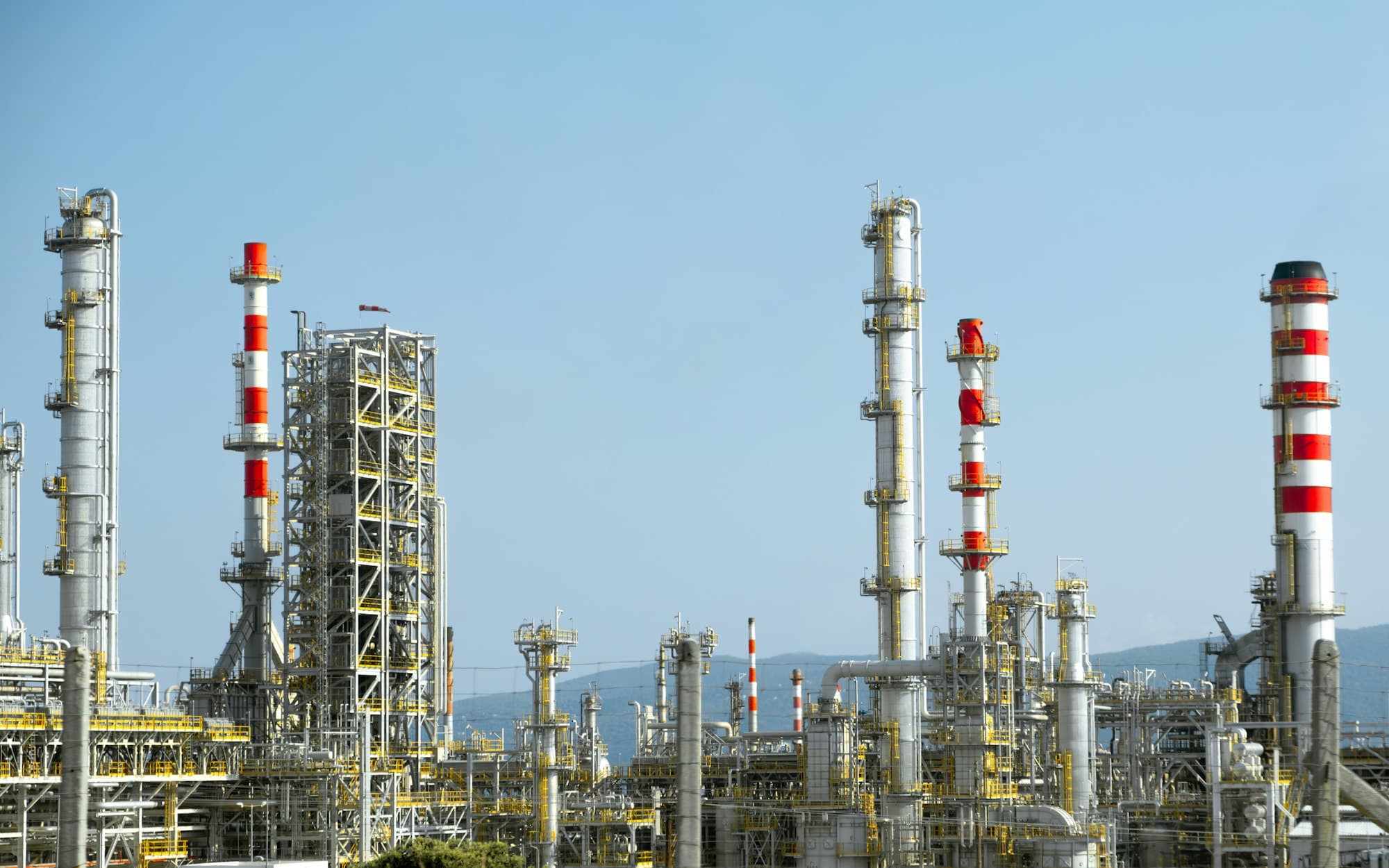 Industrial refinery with tall red and white stacks and process towers