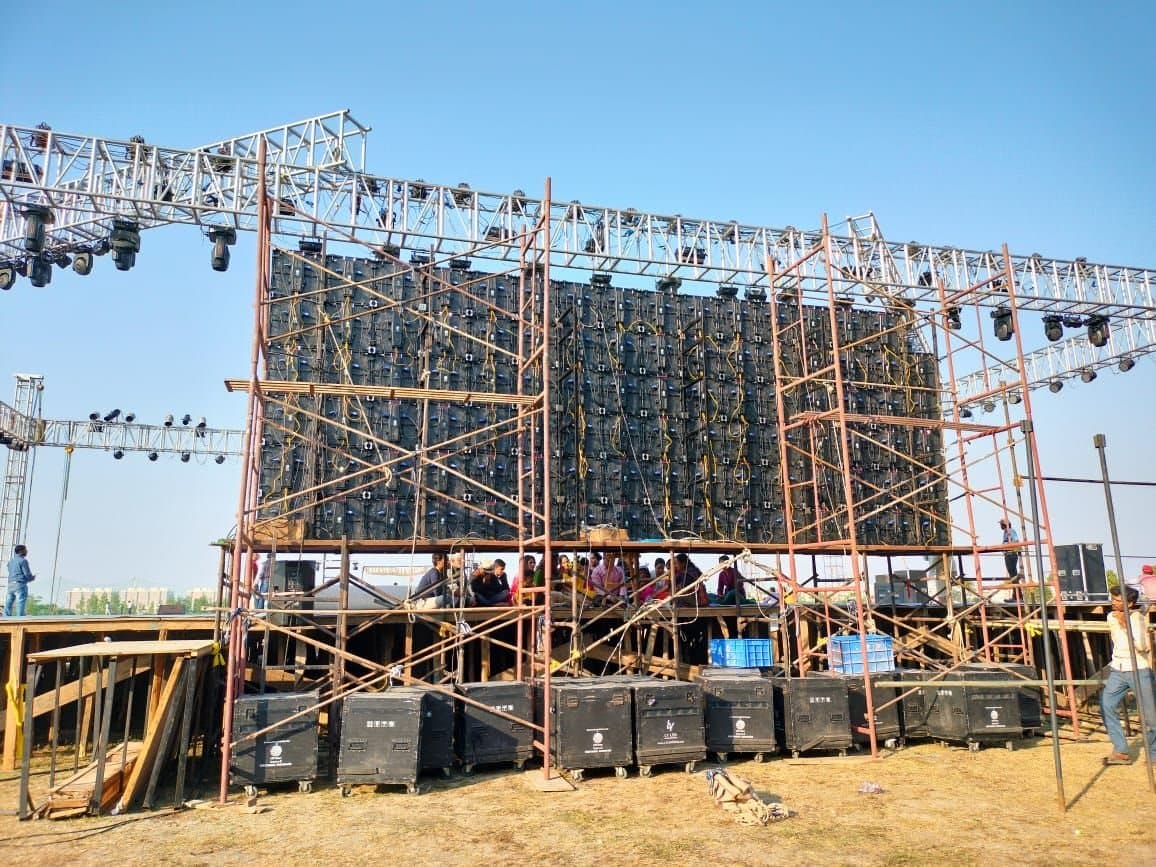 Scaffolding towers supporting a large LED video wall and lighting truss at an outdoor event
