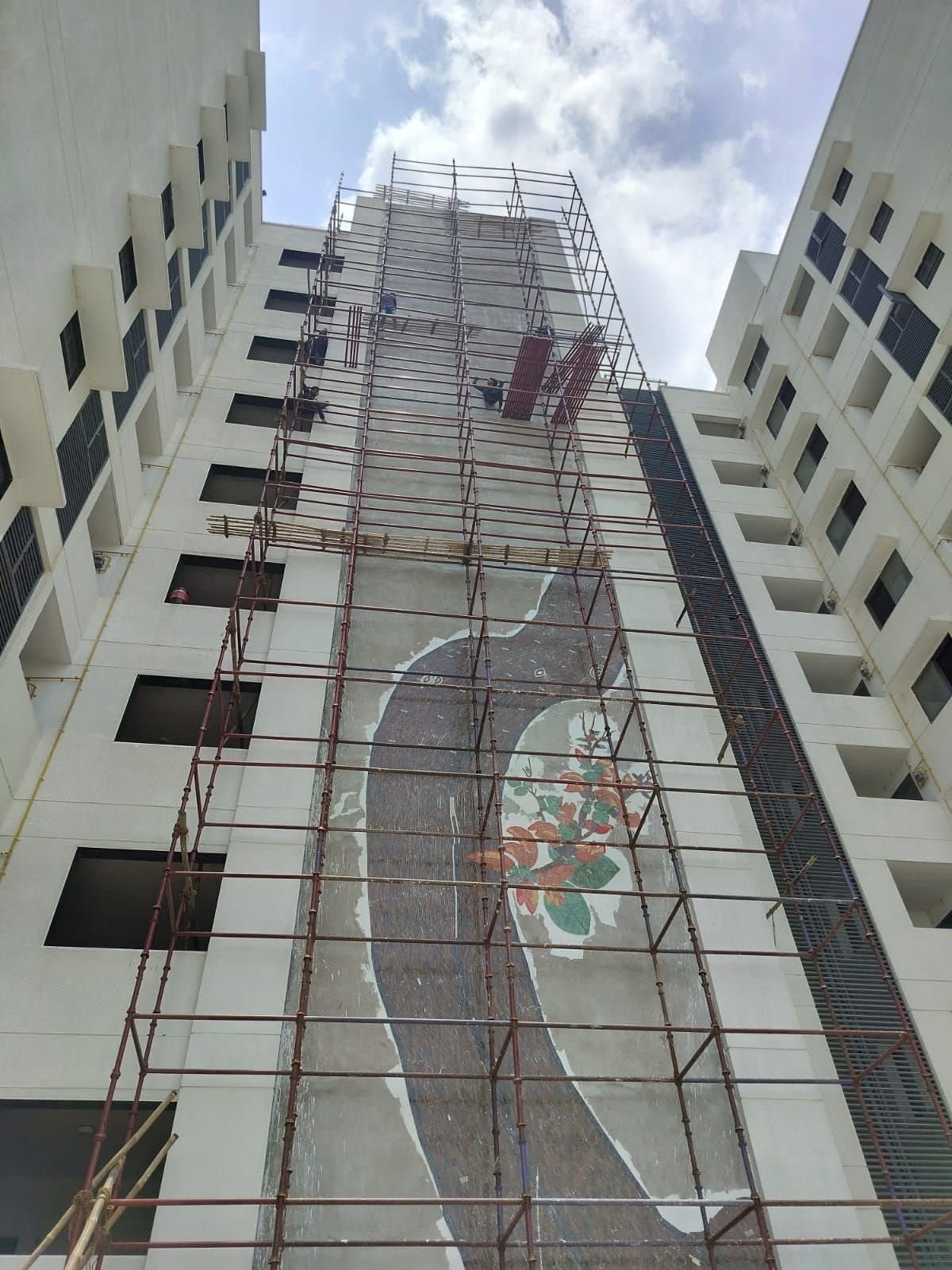 Full-height scaffolding up the facade of a residential tower during mosaic mural work