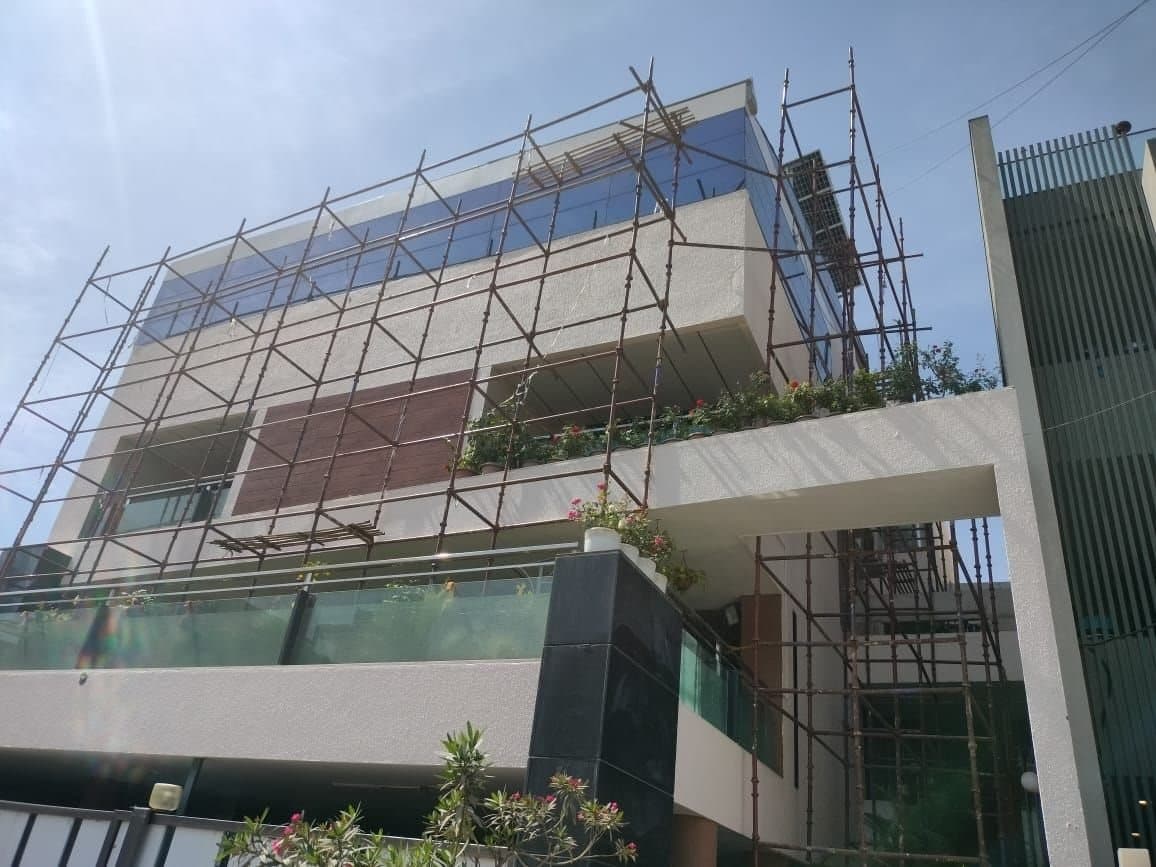 Scaffolding on the upper floors of a modern bungalow with glass balconies