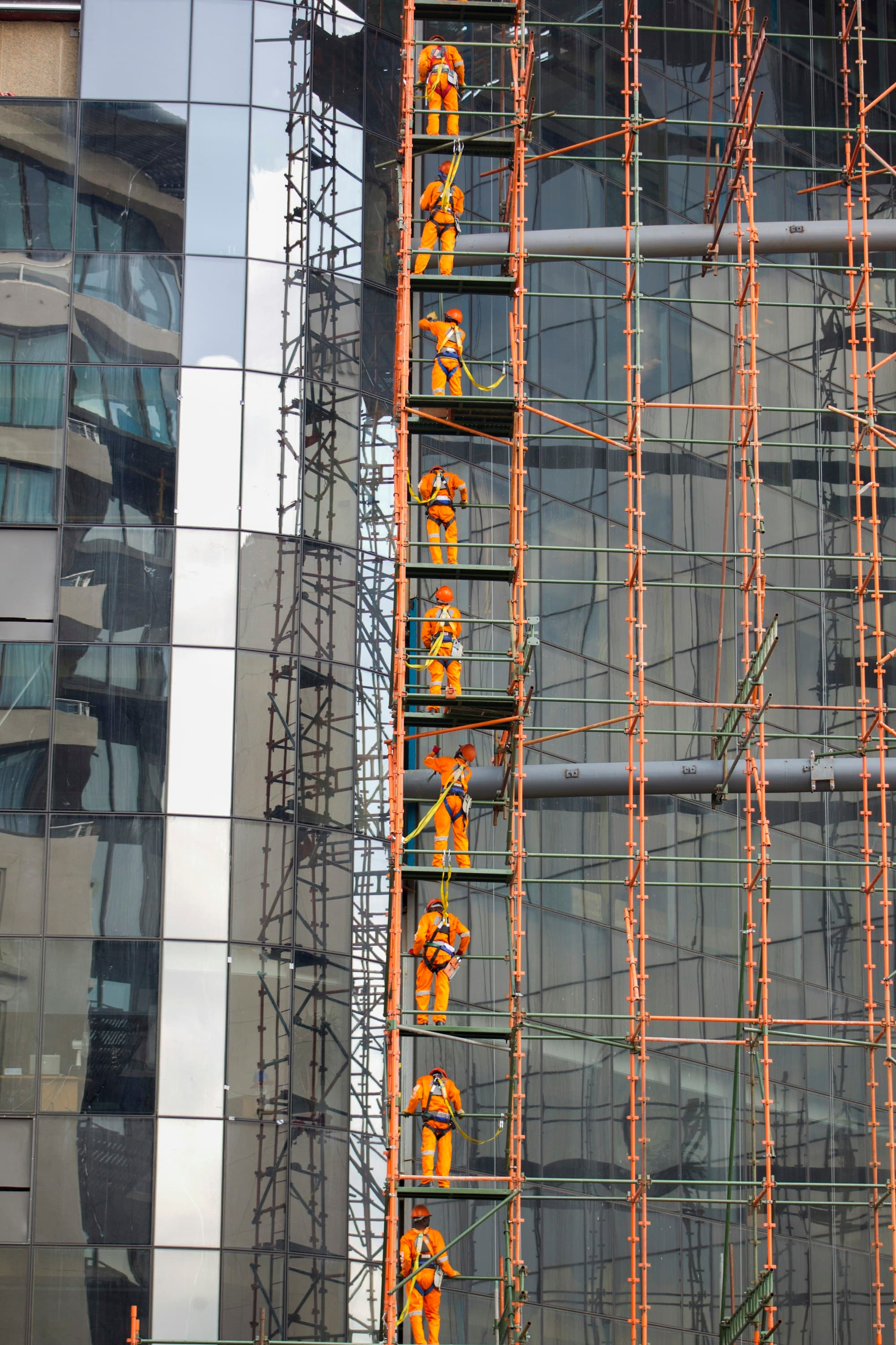 Tall scaffold tower rising alongside a glass office building
