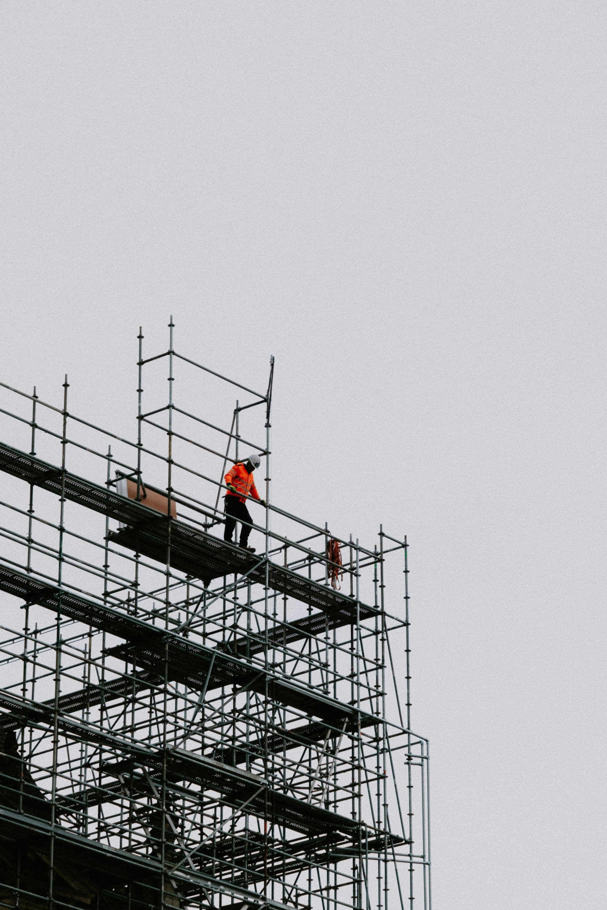 Scaffolder standing at the top lift of a scaffold against a pale sky